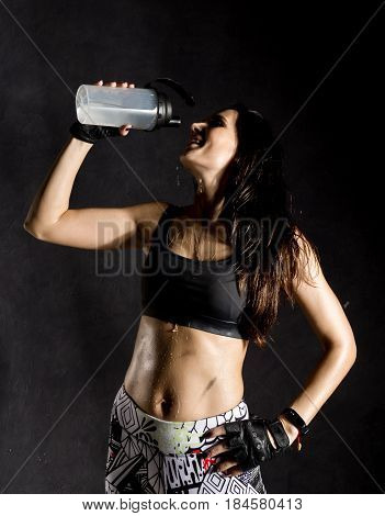 sporty female boxer or mma fighter drinking and splashing water in her face. beautiful female fitness woman on black background