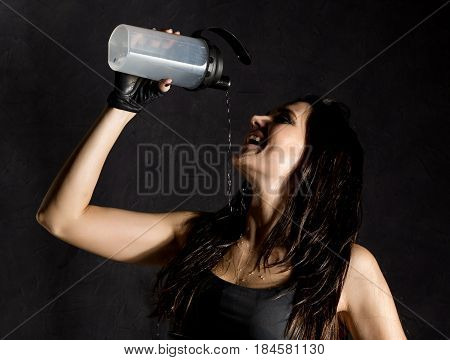 sporty female boxer or mma fighter drinking and splashing water in her face. beautiful female fitness woman on black background
