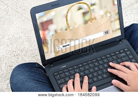 Hand typing labtop with www. on search bar over shopping bag and blur background store on line shopping search engine optimization digital marketing
