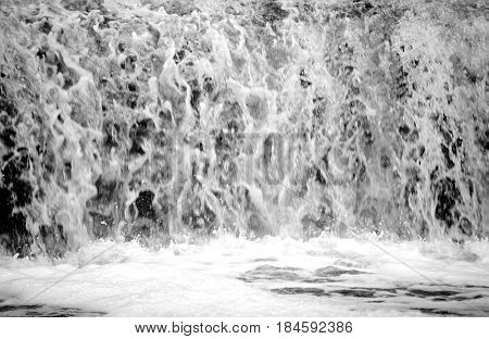 Small waterfall can be used as a background. Black and white. Blurry.