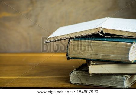 Pile of used old opened books shabby corners aged wood desk university education reading concept close up