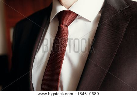 Stylish Groom Getting Ready In Morning, Putting On Brown Suit White Shirt And Red Tie Close Up. Morn