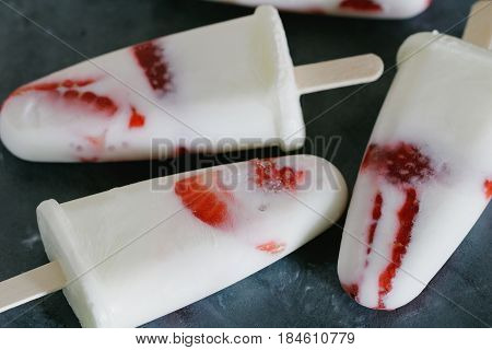 Homemade ice cream popsicles with fresh strawberries on the grey background