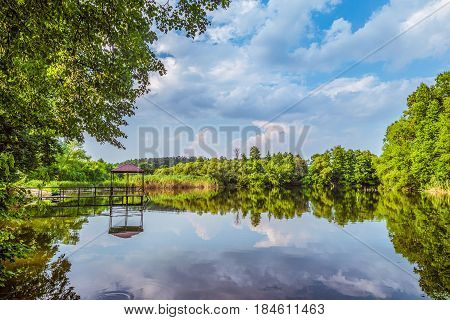 Lake in a forest with a small pier for walking pedal catamaran on the shore. Dock for pedal boat and a quiet holiday in nature.