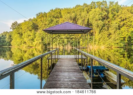 Small wooden pier for pleasure pedal catamaran on the forest lake shore. Dock for pedal boat and a quiet holiday in nature. Disappearing into the distance perspective.