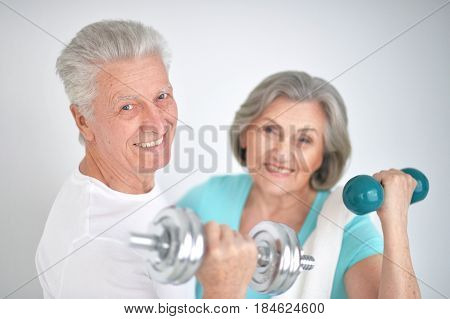 Beautiful elderly couple in a gym with dumbbells