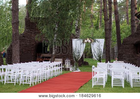 Beautiful Wedding Ceremony Outdoors. Decorated Chairs Stand On The Grass. Wedding Arch Made  Flowers