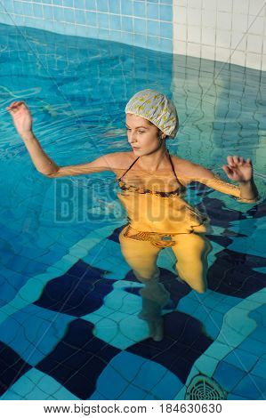 Young beautiful woman with cap relaxing in swimming pool