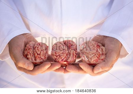 Hands holding a plastic punnet of three brains