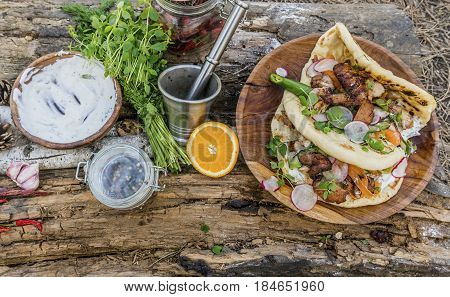 Burrito or shawarma with grilled chicken and vegetables on wooden background in forest. Natural healthy food concept.