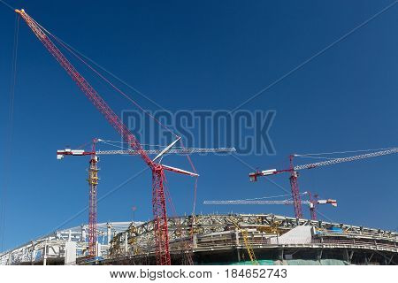 Football stadium construction with cranes and blue sky in Moscow.