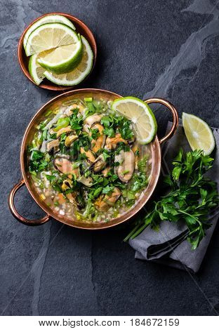Latin American ceviche o mariscal - raw seafood cold soup wish mussels, clams, prawns, lime, onion in copper bowl on slate background. Seafood shellfish ceviche. Traditional dish of Peru or Chile