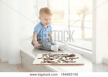 Cute little child playing with letters at home