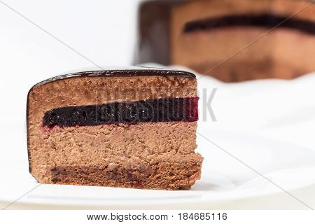 Slice of chocolate mousse cake with currant jelly and mirror glaze