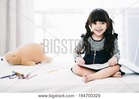 Portrait of beautiful kid having activity on her bed.