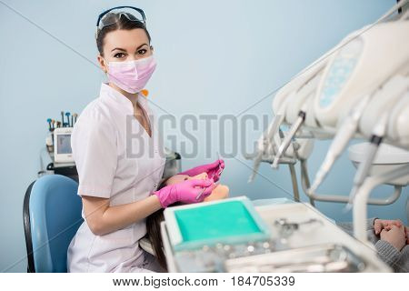 Female Dentist With Dental Tools - Mirror And Probe Treating Patient Teeth And Looking To The Camera