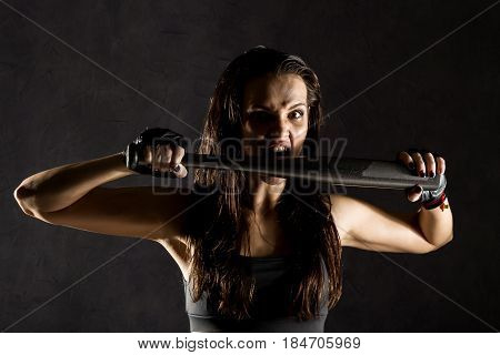 sexy athletic woman with baseball bat on dark background in the beam of a searchlight.