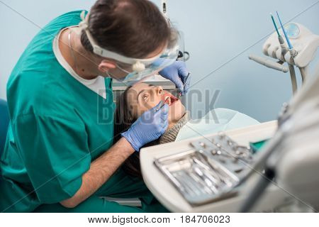 Male Dentist With Dental Tools - Mirror And Probe Checking Up Patient Teeth At Dental Clinic Office.