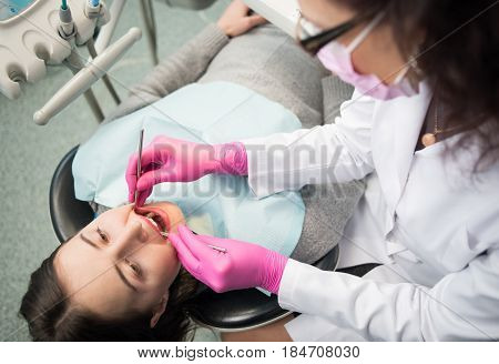 Young Woman Having Dental Check Up In Dental Clinic. Dentist Examining A Patient's Teeth With Dental