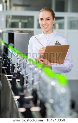Female worker near conveyour at a water factory
