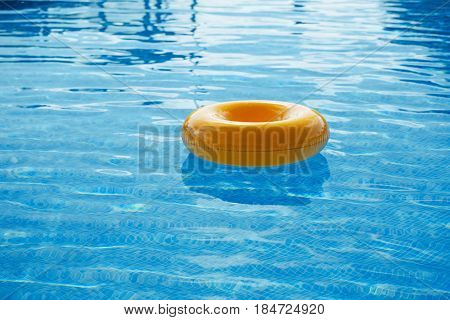 floating ring on blue water swimpool with waves reflecting in the summer sun