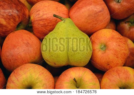 A green pear lies on red juicy apples