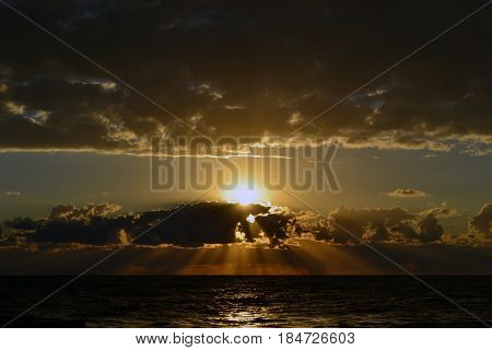 Sunset over the sea behind the clouds