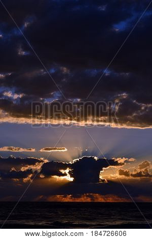 Sunset over the sea behind the clouds