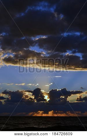 Sunset over the sea behind the clouds