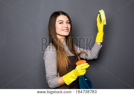 Young Woman Use Spray While Cleaning Up House Posing For Camera On Grey Background