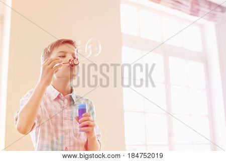 Boy blowing bubbles at home