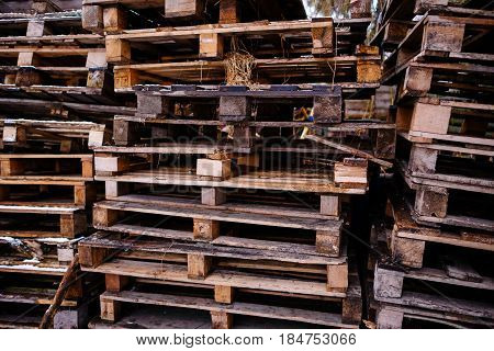 Bunch of old wet colored wooden pallets on green grass