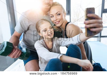 Girl Taking Self Portrait With Parents At Fitness Center