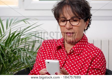 mature woman reads a message on her phone
