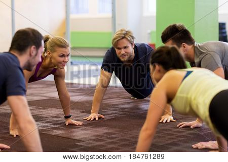 fitness, sport, exercising, training and healthy lifestyle concept - group of people doing straight arm plank in gym