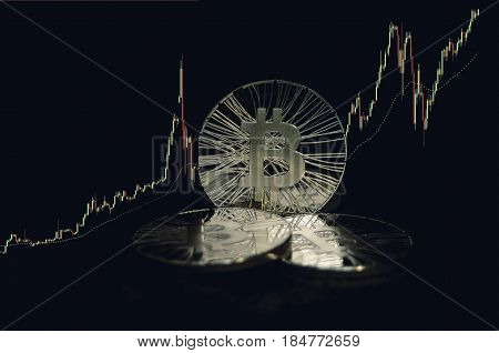 Three Shiny Bitcoin Coins On Black Background With Trading Chart