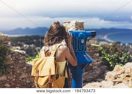 Hipster tourist look observant binoculars telescope on panoramic view lifestyle concept trip traveler with backpack on background mountain and blue sea landscape horizon young girl hiker pointing hands
