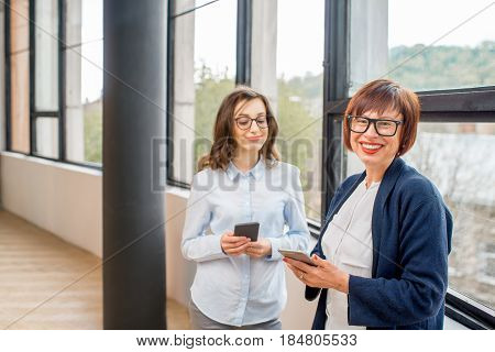 Portrait of a young and older businesswomen standing near the window at the office