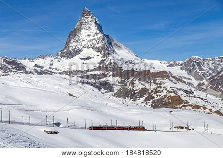 Zermatt, Switzerland - April 12, 2017: A red train in front of the snowy Matterhorn mountain