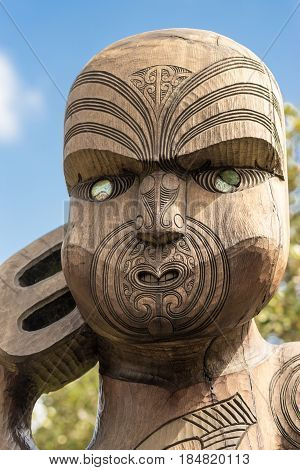 Auckland New Zealand - March 2 2017: Face closeup of wooden sculpture of Te Kawerao A Maki the spiritual guardian (Manawhenua) of Karakare Beach. Blue sky.
