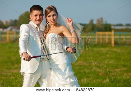 Groom Holds A Golf Mashy Posing With A Bride