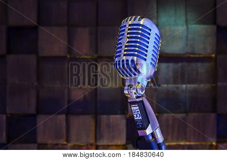 MINSK BELARUS - SEPTEMBER 29 2015: Silver old fashioned stage microphone- SHURE Super 55 Deluxe against wood background. Voice recording concept Retro style mic ready to rock