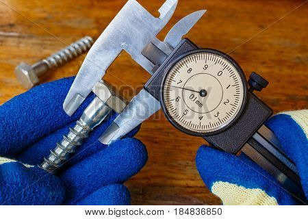 Measurement of the bolt head by a master in gloves with a slide caliper