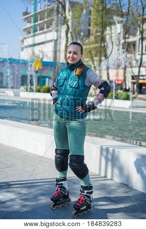 Beautiful and happy Roller Girl skating in the park. She is looking at the camera
