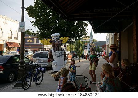 HARBOR SPRINGS, MICHIGAN / UNITED STATES - AUGUST 4, 2016: An entertainer in a moose costume greets visitors outside Kilwin's Candy Store, during the Street Musique event on Main Street in downtown Harbor Springs.