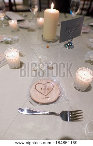 Wedding reception centerpiece with a location seating sign, candles, and flowers ont he table.