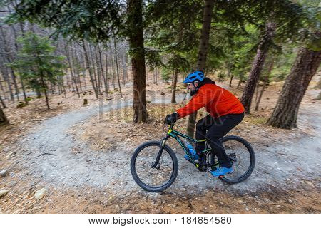 Mountain biker riding on bike in early spring mountains forest landscape. Man cycling MTB enduro flow trail track. Outdoor sport activity.