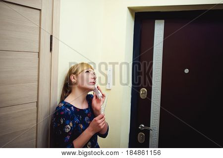 Blonde Woman Answers The Intercom Call, Hold The Phone To His Ear, Waiting For The Arrival Of The Lo
