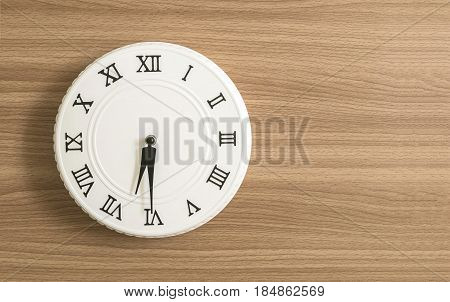 Closeup white clock for decorate show half past six or 6:30 a.m. on wood desk textured background with copy space