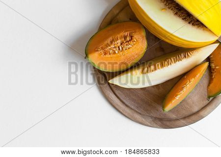 canary and cantaloupe melon on a wooden board and a white background